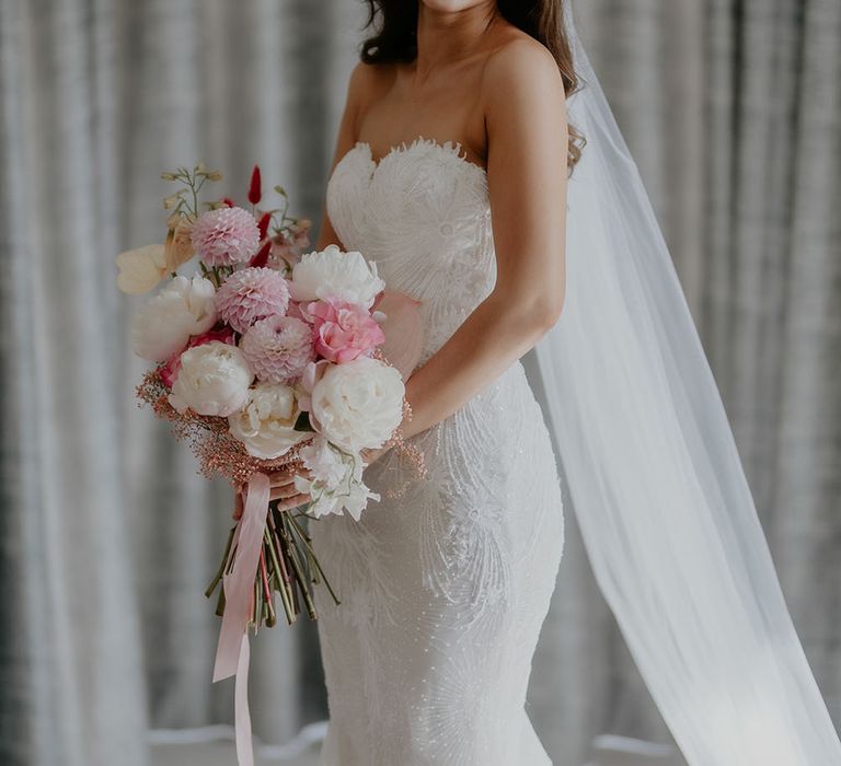 Bride wears fitted lace Pronovias wedding dress with sweetheart neckline and holds white and pink flower bouquet 