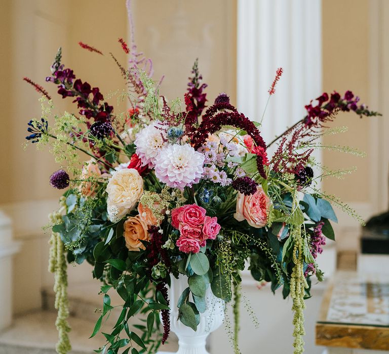 Brightly coloured floral bouquet complete with green foliage in white vase 