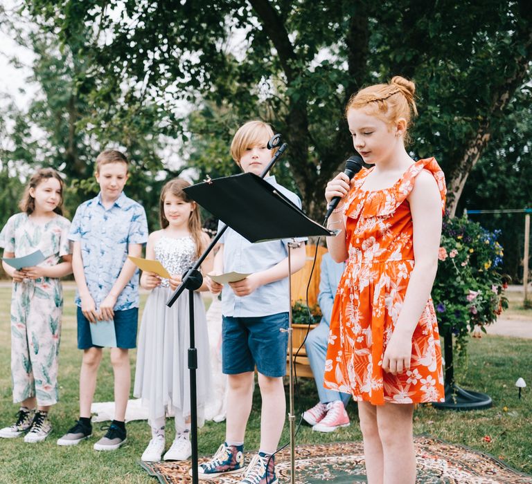 Little girl speaks during wedding ceremony outdoors 