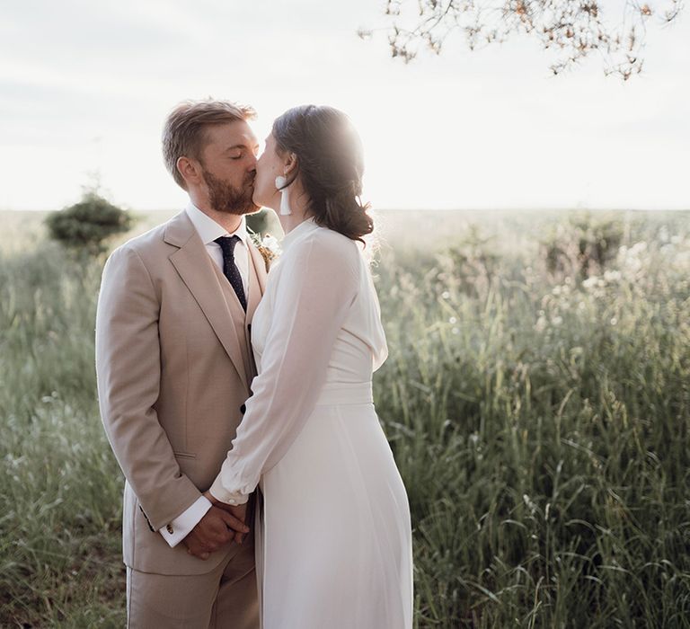 Bride wearing tassel earrings kissing the groom for a cute couple portrait 