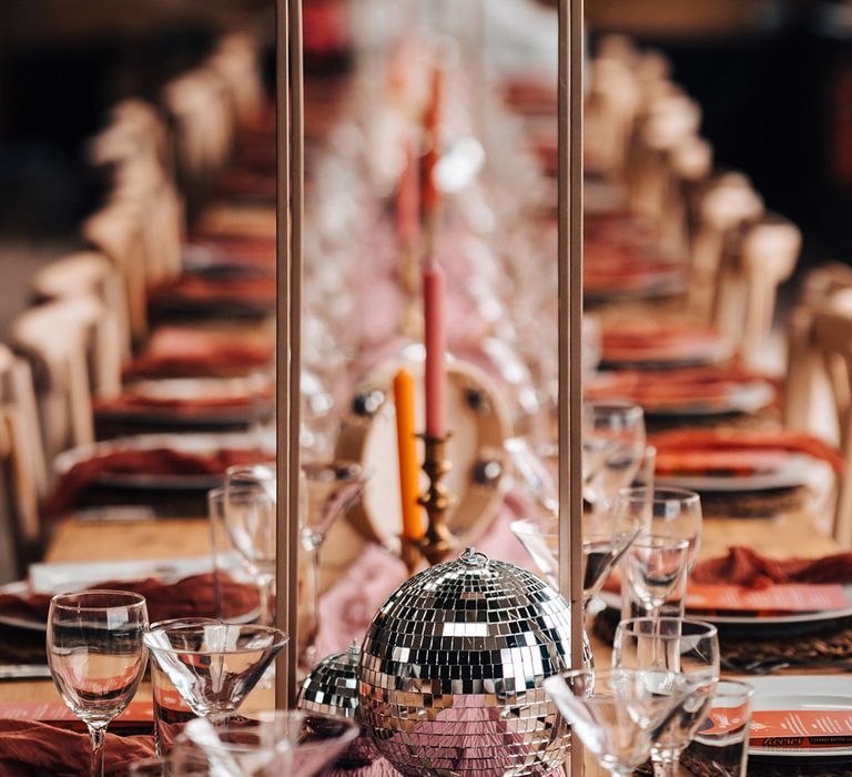 Disco ball table decor with pink and red table settings and tall tropical flower centrepieces 