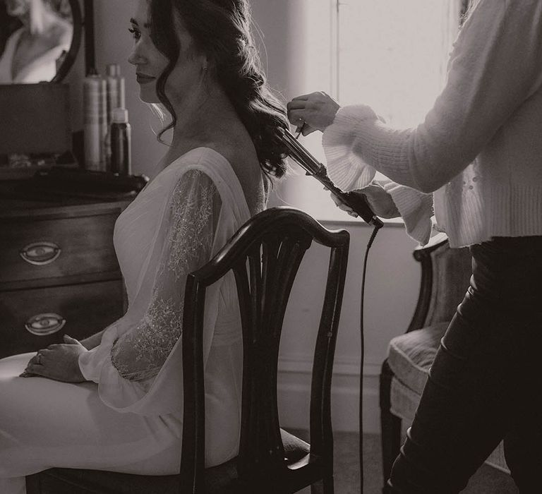 Bride gets her hair done for her rustic winter wedding in a half up half down hairstyle 