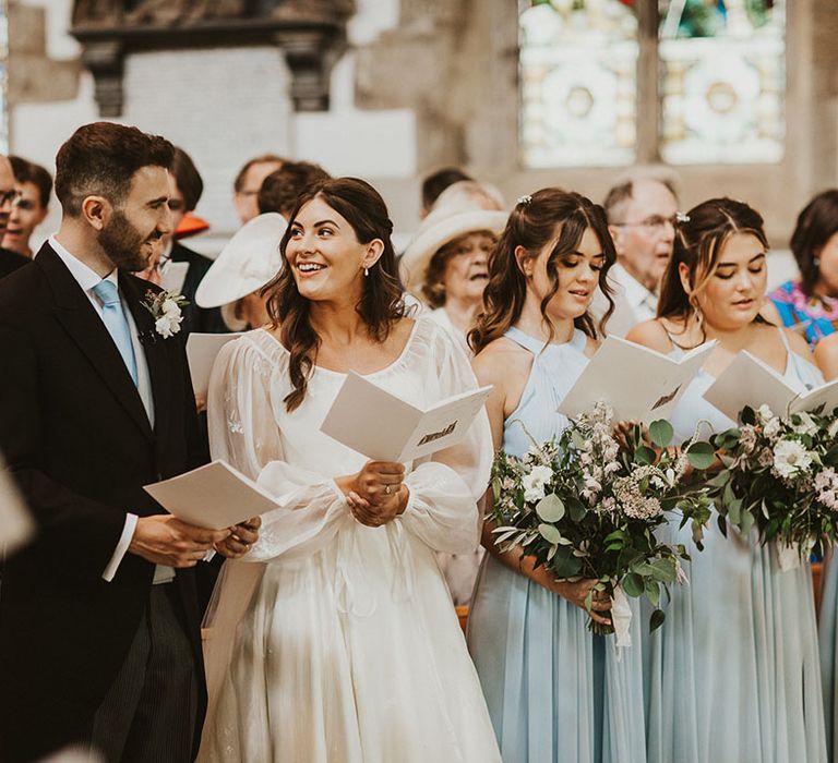 Bride and groom look at each other as they sign hymns for their church wedding ceremony