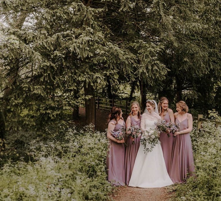 Bride in a high neck long sleeve wedding dress standing with the bridesmaids in taupe dresses 