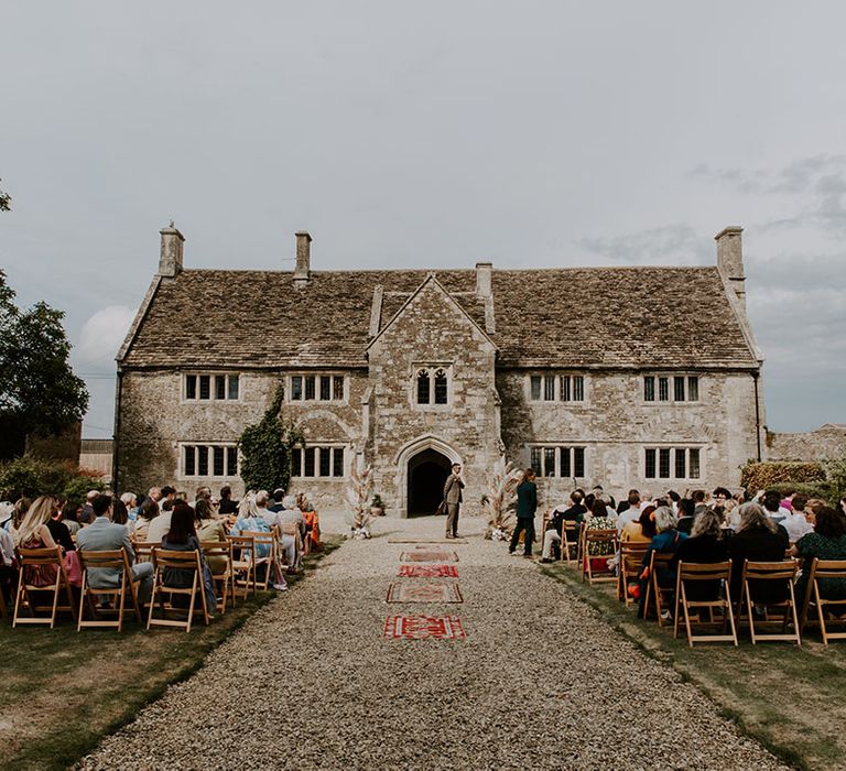 Outdoor wedding ceremony complete with Moroccan styled rugs lining the aisle 