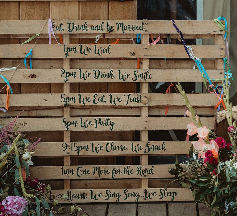 DIY wooden pallet wedding order of the day wedding sign with bunting and colourful flowers 