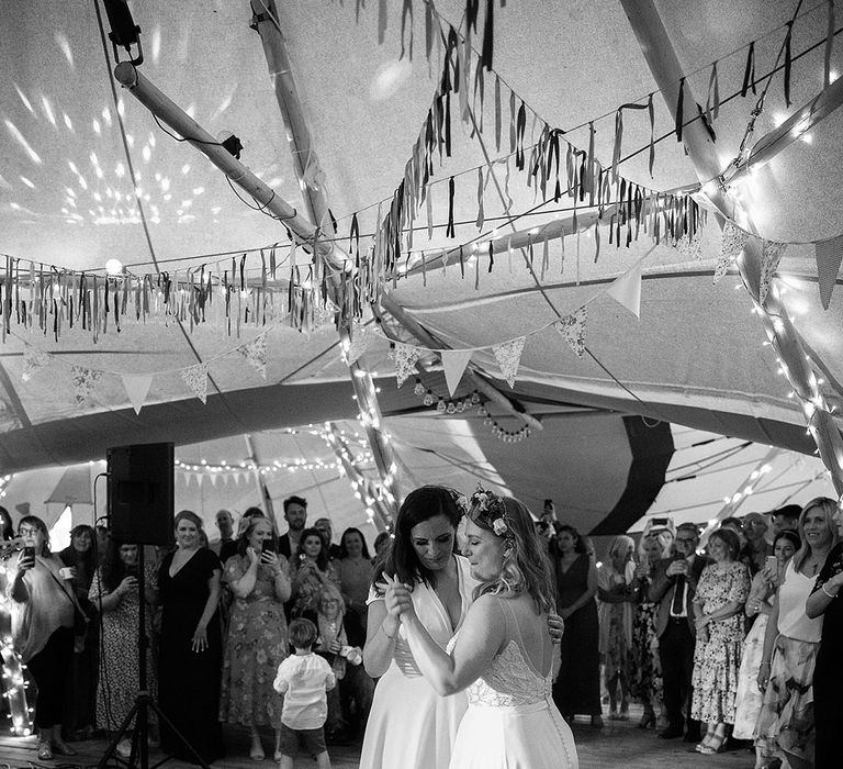 Brides share their first dance together under fairy lights and their DIY streamer decor 