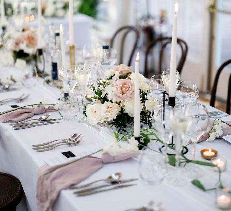 Small floral arrangements line the table complete with pink fabric napkins 