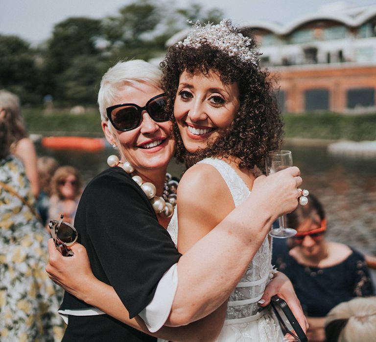 Curly haired bride hugs wedding guest in sunglasses 