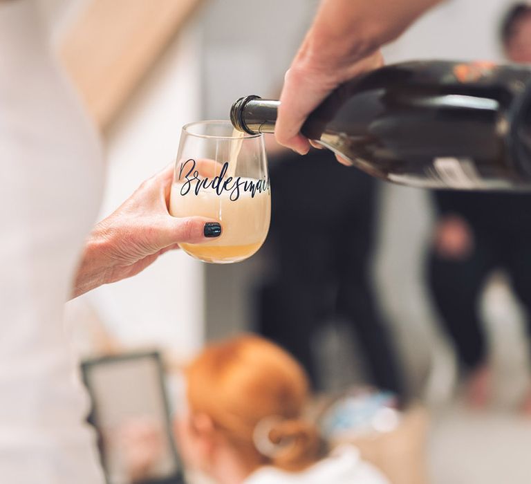 A glass personalised for the bridesmaids being used to make mimosas for the bridal party in the morning 