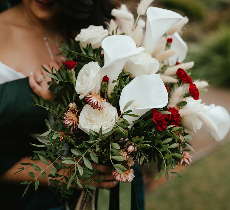 Bride carries white orchid bridal bouquet complete with roses, green foliage and bunny tails 