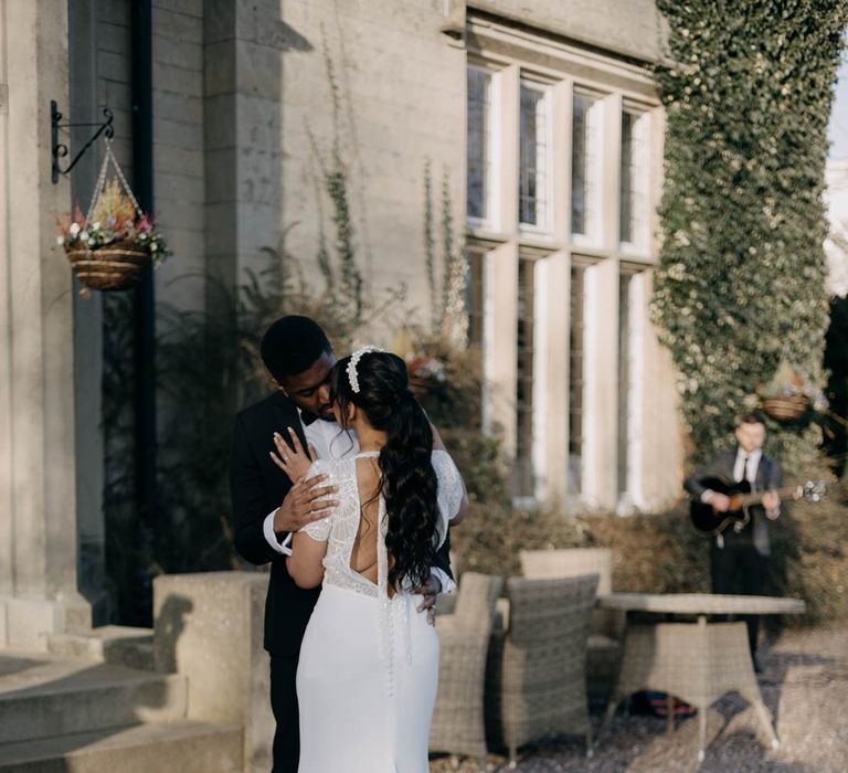 Bride in puddle train wedding dress with lace open back embracing groom at elegant Manor House wedding in Yorkshire