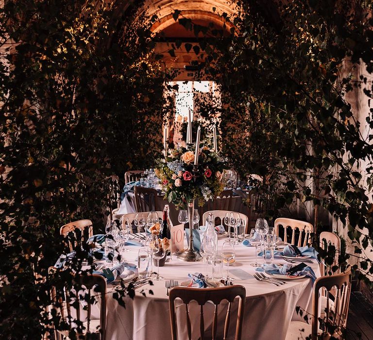 Romantic wedding tablescape with blue places settings including blue napkins, menus, and tall table centrepieces 