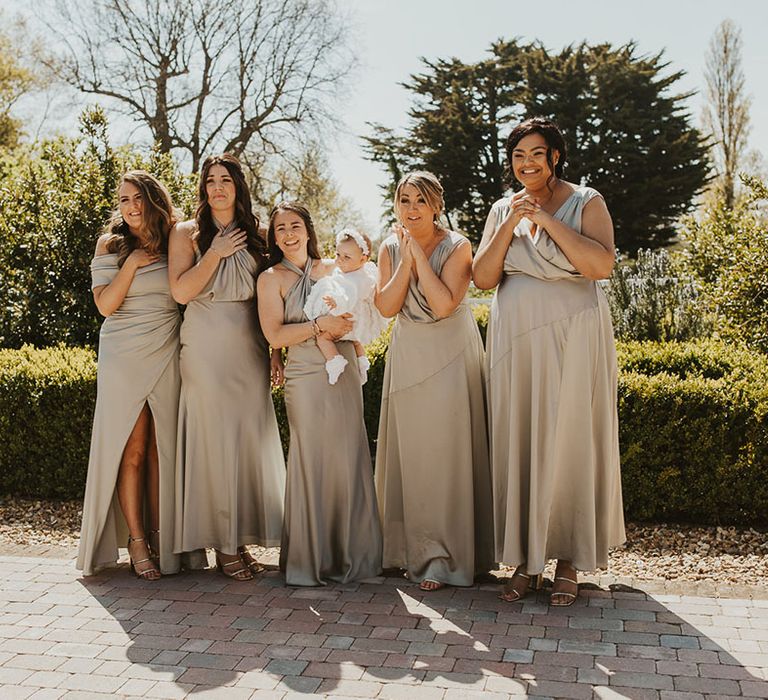 Bridal party with golden mismatched bridesmaid dresses get their first look at the bride 