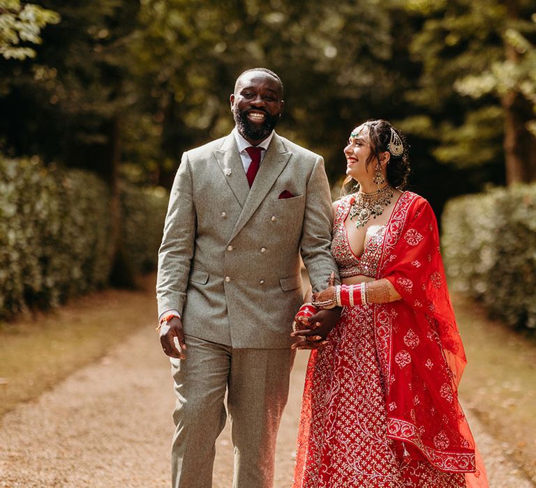 Bride in red and gold wedding lehenga with the groom at their Larmer Tree Gardens wedding 