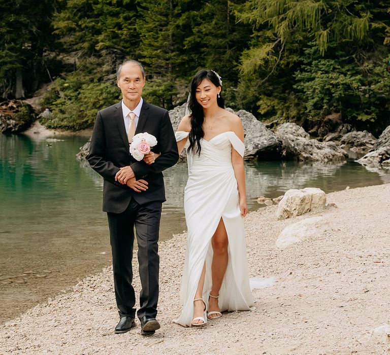 Father of the bride walks the bride to the outdoor wedding ceremony 