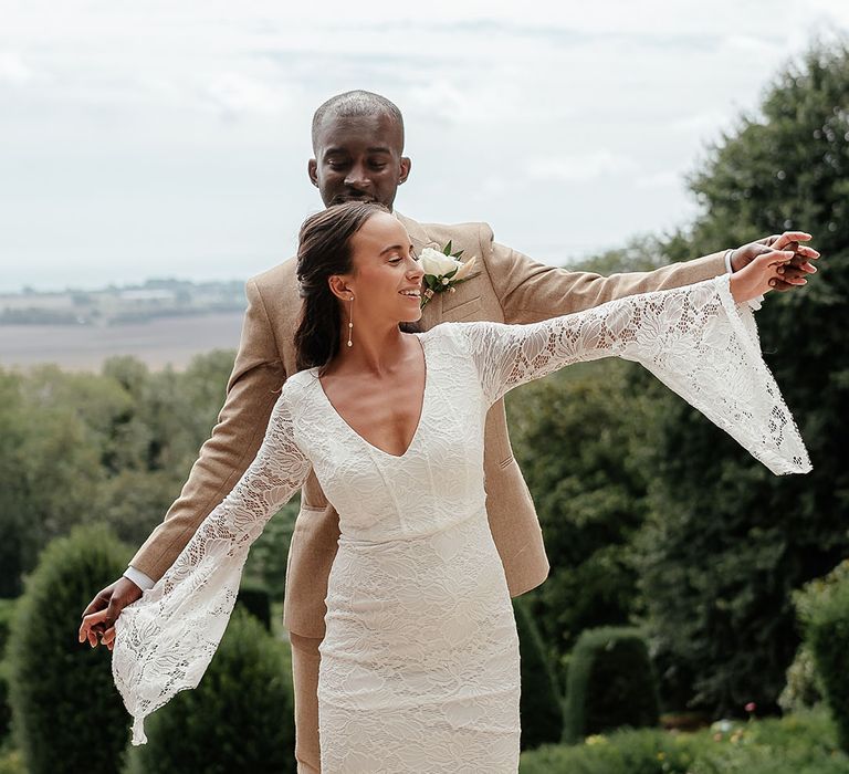 Bride in a boho lace wedding dress posing with the groom with the beautiful Kent landscape in the background 