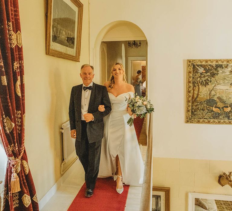 Father of the bride in black tuxedo escorts the bride to the ceremony 