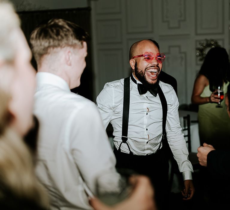 Wedding guest at the reception wearing pink heart shaped sunglasses 