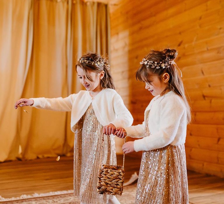 Flower girl wearing gold sequin flower girl dresses with white cardigans and metallic wedding flower crown 