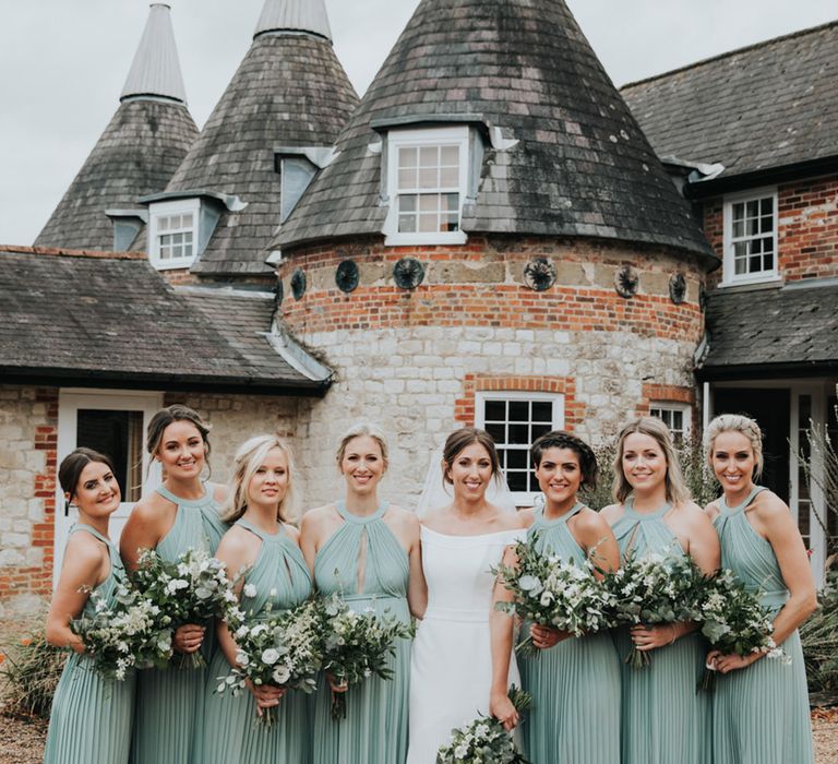 Bury Court Barn wedding with bridesmaids wearing sage green halter neck bridesmaid dresses with pleated skirt 