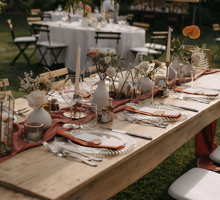 Boho wedding tablescape for outdoor wedding breakfast with rustic lighting and minimalist table decor with burnt orange and terracotta theme 