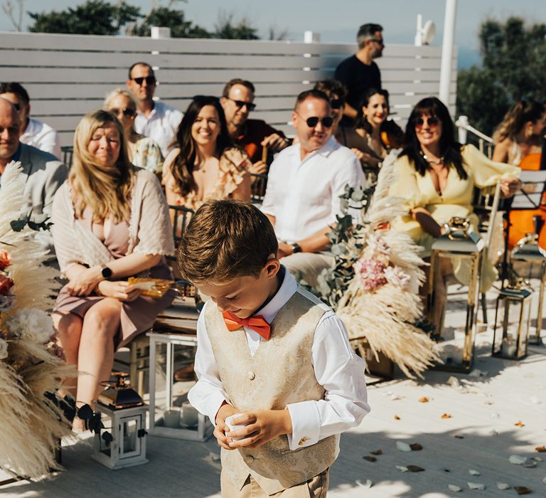 Page boy in beige suit and orange bow tie for destination wedding 