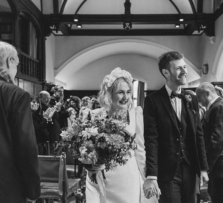 Newlyweds walk back down the aisle as a married couple at their registry office style wedding 