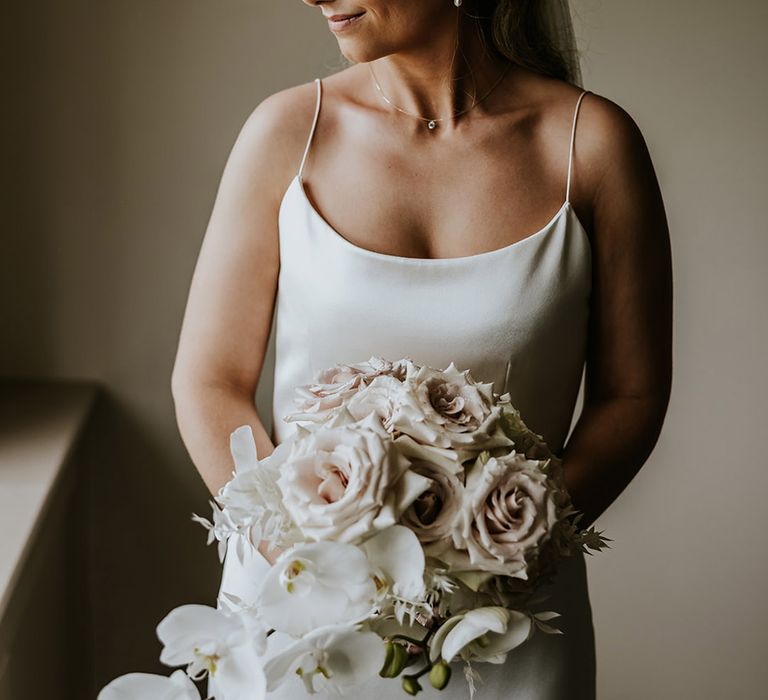 Bride holding pink rose bouquet with white orchids in satin slip dress for minimalist bride 