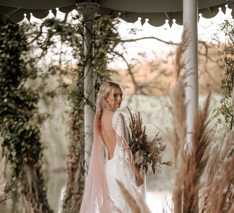 The Bride's blush pink veil trails over her lace boho dress