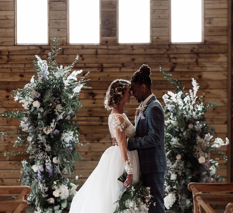 The bride and groom stand at the altar of their barn wedding