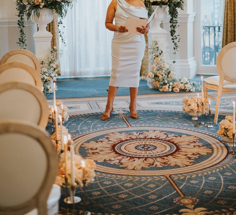 Jennifer Patrice wedding celebrant standing at the altar flanked by peach and white wedding flowers 