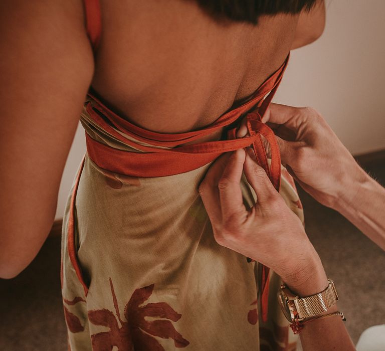 The groom helping Sirjana get dressed in a dress her mother made for her