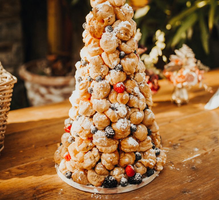 Towering croquembouche decorated with fresh berries and icing sugar