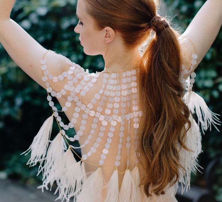 White redheaded bride with a sleek ponytail in a disc, chain and feather festival coverup | Rebecca Goddard Photography