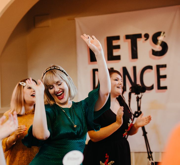 Wedding guest in a dark green dress dancing during the wedding ceremony 