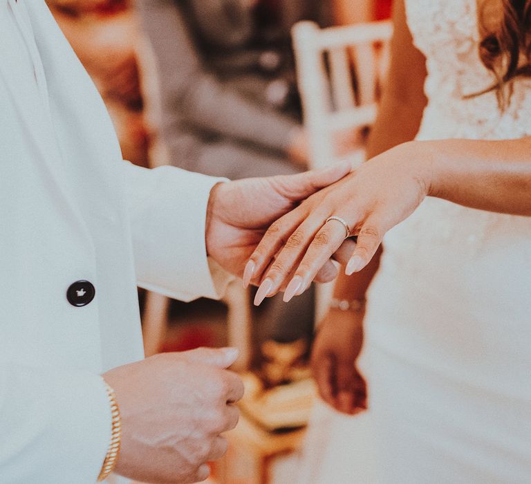 Groom holds brides hand before placing ring on finger