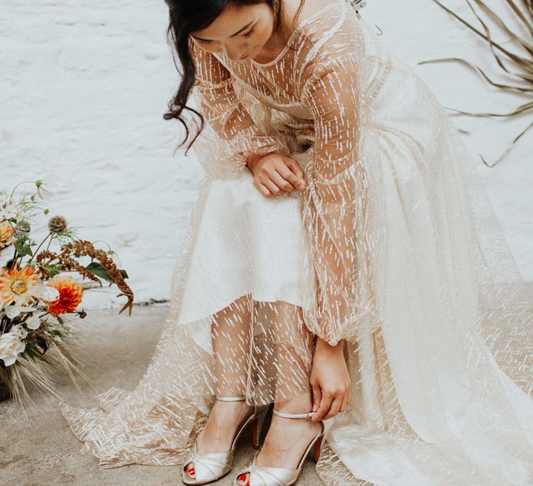 The bride wearing a floral bridal headpiece and a layered long sleeve wedding dress with sparkle details