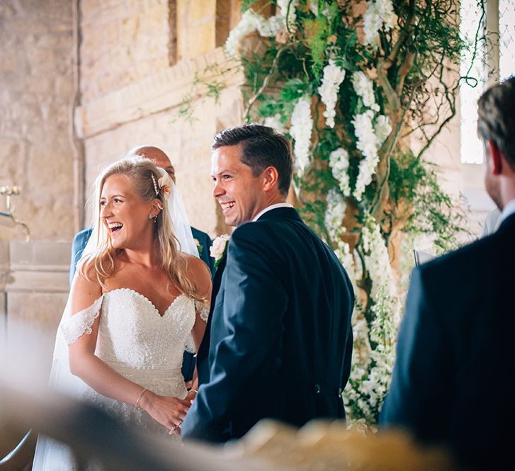 Bride and groom holding hands and laughing at Warwickshire church wedding