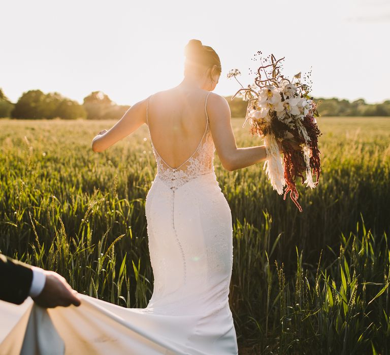 Bride & groom walk through fields during golden hour