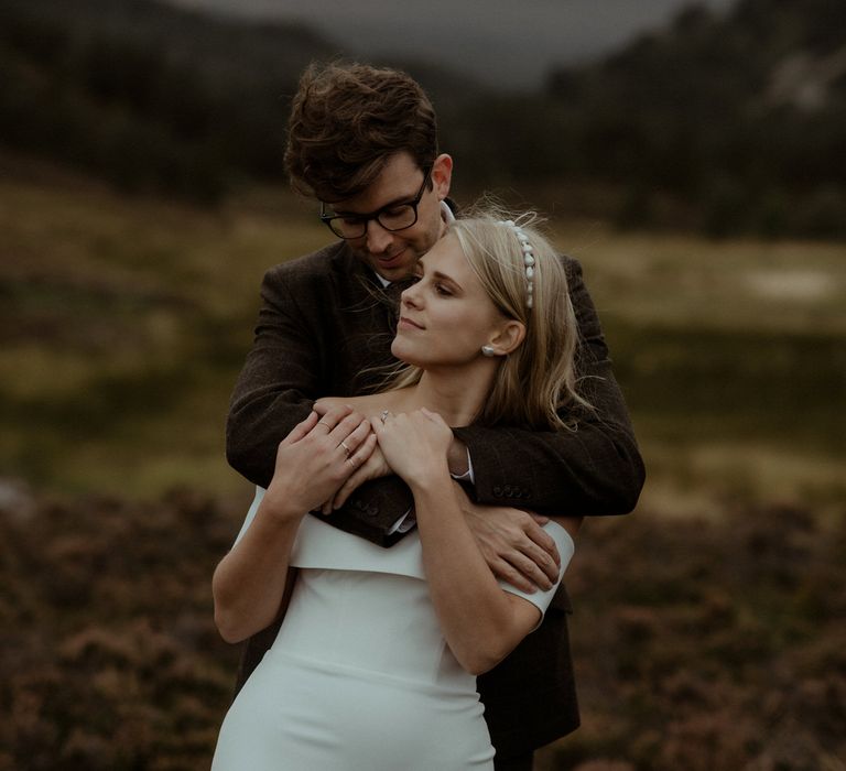 Groom puts his arms around bride in the Scottish countryside