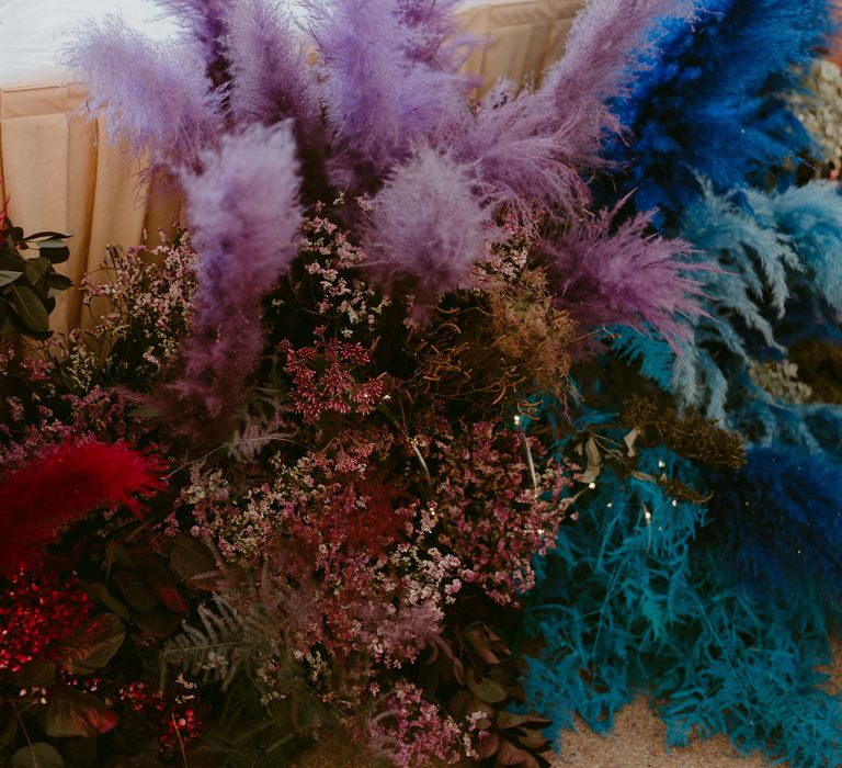 Purple, blue and pink pampas grass floral installation at wedding breakfast table