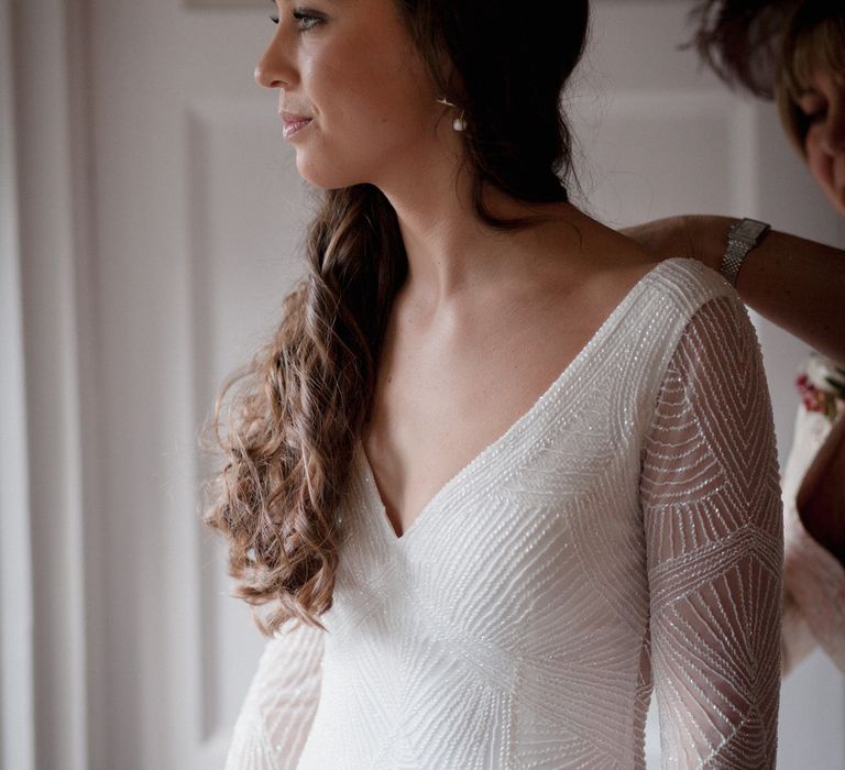 Bride wearing beaded long sleeved, low neck bridal gown