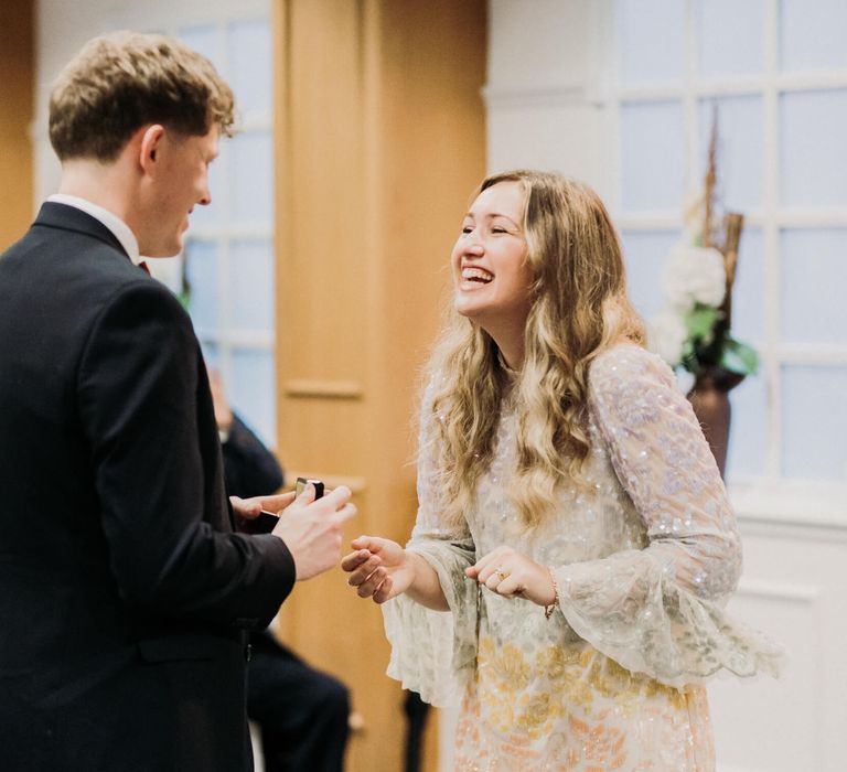 Bride smiling as groom exchanges rings at Manchester registry office Wedding