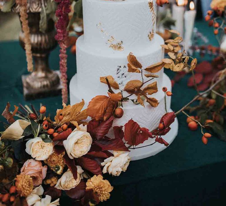 White wedding cake with Autumn colour wedding flowers and leaves