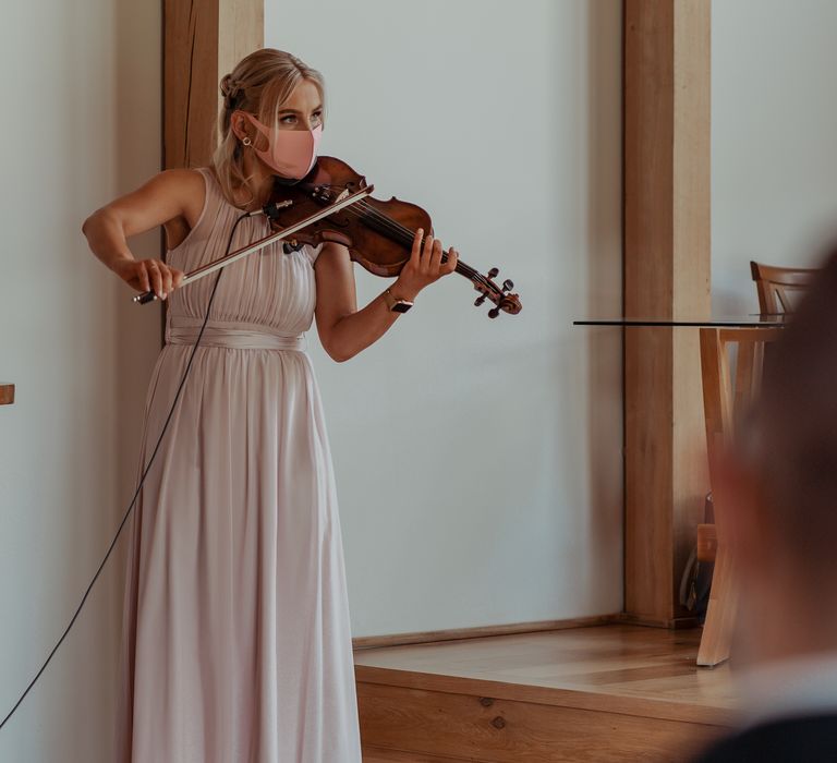 Violinist plays whilst wearing blush pink face covering at wedding ceremony