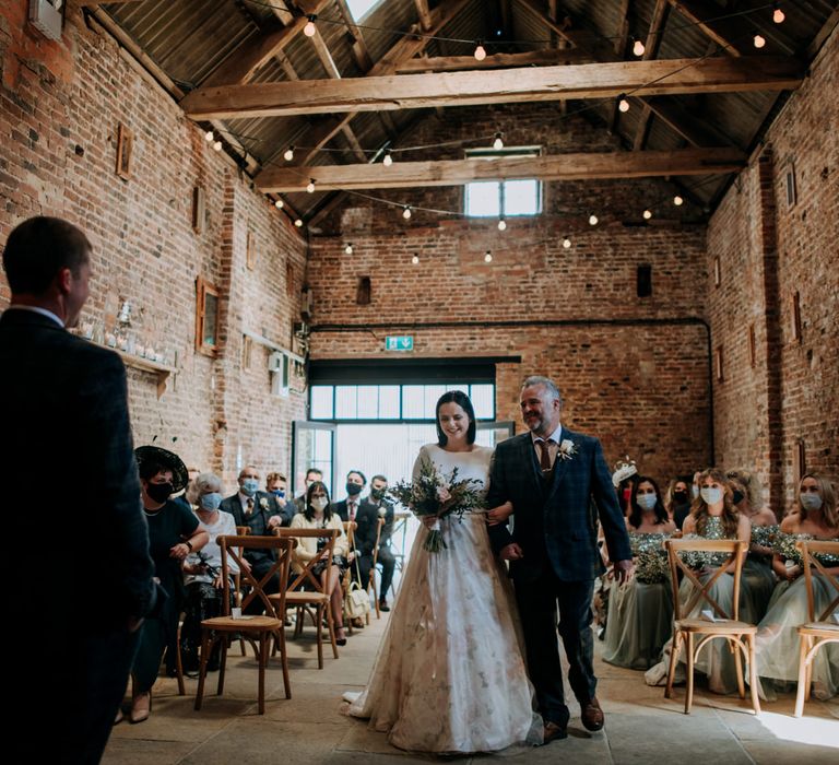 Father of the bride walking his daughter down the aisle in a couture wedding dress with floral skirt design 