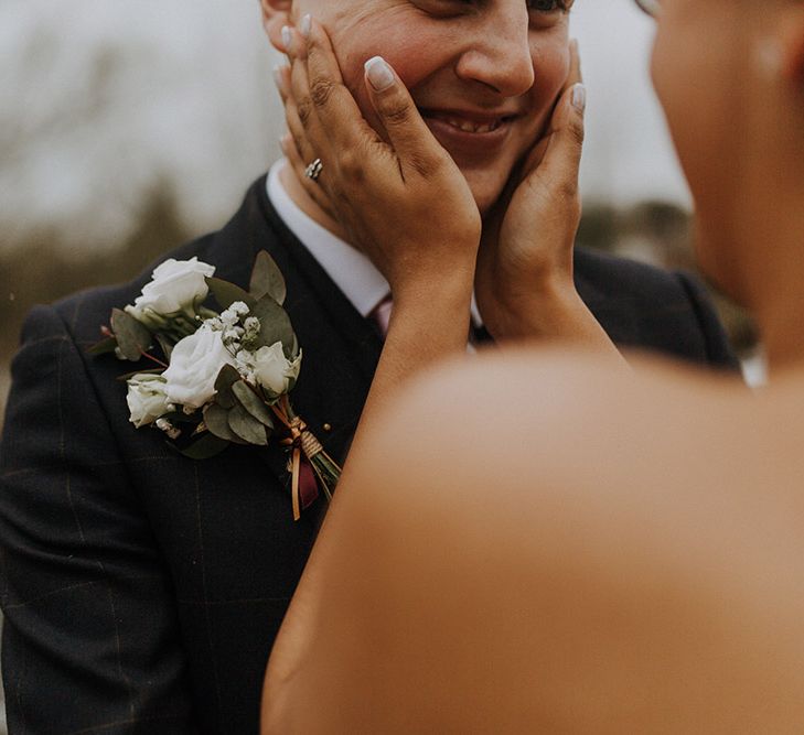 A bride cups her grooms face in her hands for wedding portrait.