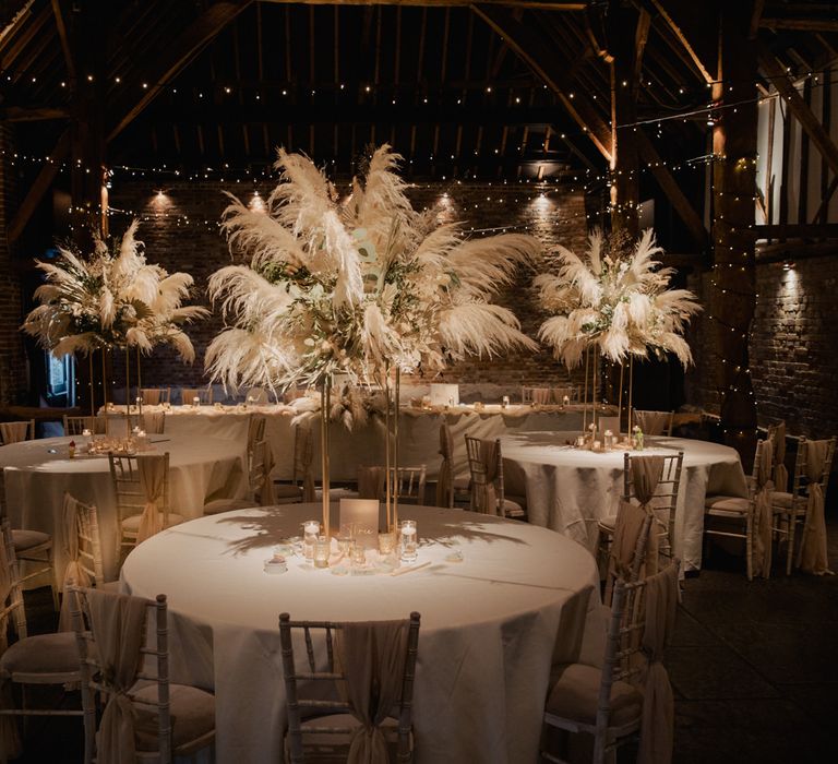 Cooling Castle Barn wedding reception with fairy lights and pampas grass centrepiece table decor 