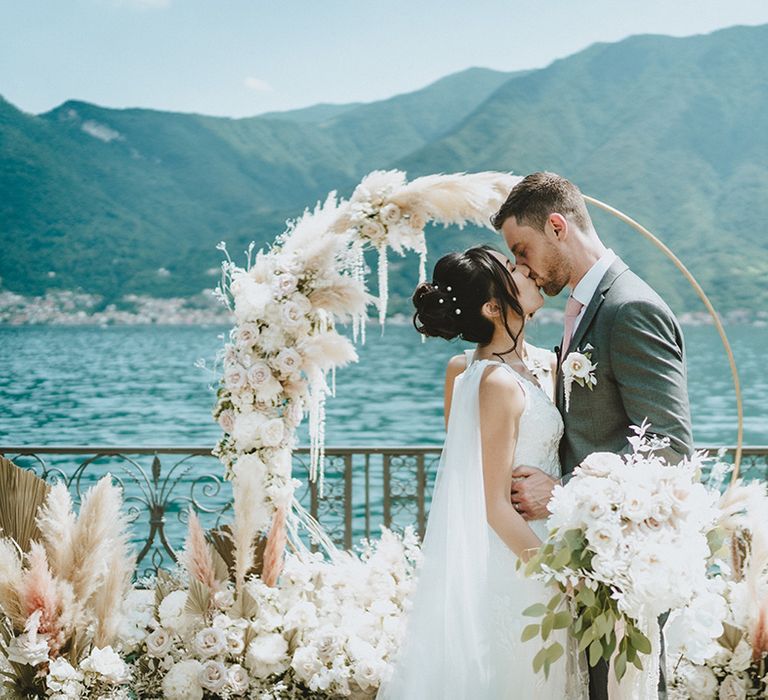 Bride & groom kiss in front of pampas grass floral installation on their wedding day